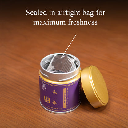 Open Kuwacha mulberry leaf tea tin on a wooden surface with the gold lid beside it, revealing the inner foil bag, text 'Sealed in airtight bag for maximum freshness'.