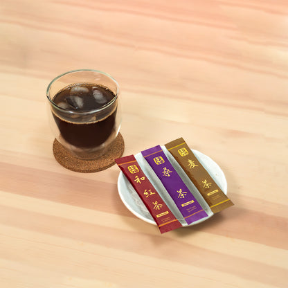 Wakocha, Kuwacha and Mugicha sticks on a white dish beside a glass of iced brown tea on a cork coaster.