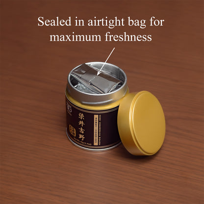 Open Somei-Yoshino Ceremonial Matcha tin on a wooden surface with the gold lid beside it, revealing the inner foil bag, text 'Sealed in airtight bag for maximum freshness'.